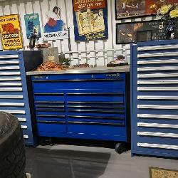 Large Matco rolling tool chest flanked by matching drawer cabinets with automotive signage above.