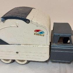 Vintage Structo hydraulic refuse truck with gray cab, white body and rear loading mechanism. Whitewall-style tires with visible age-related wear and soiling.