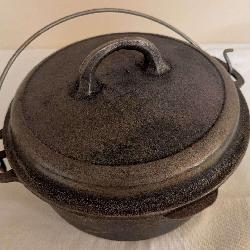 Vintage Wagner cast iron Dutch oven with fitted lid and wire bail handle. Appears to primarily need cleaning and reseasoning.
