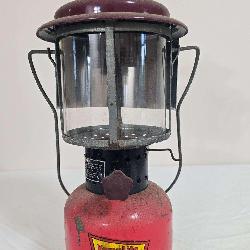 Vintage KampLite No. KFL-2 pressure lantern with red painted fount, dark maroon ventilator, clear glass globe and black wire frame/bail assembly. Shows paint loss, oxidation and general age-related we