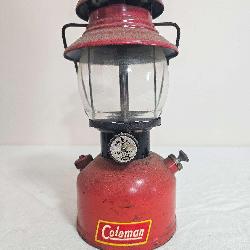 Vintage Coleman Model 200A pressure lantern with red painted fount, matching red ventilator, clear glass globe and black wire frame; marked 6/52. Coleman decal remains visible on the fount with paint 