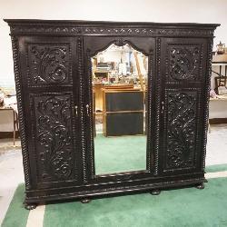 1217	ORNATE CARVED 3 DOOR CABINET WITH BEVELED GLASS CENTER MIRROR AND ADJUSTABLE SHELVES IN AN EBONIZED FINISH, APPROXIMATELY 84 IN X 26 IN X 73 IN H